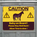 Caution sign with horse illustration and text on a yellow background