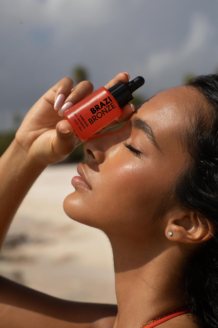 Woman on the beach holding the Sunkissed Self-Tan Serum